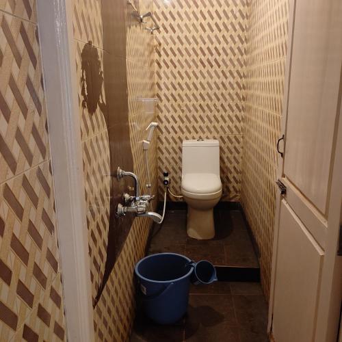 a small bathroom with a toilet and a bucket at Vanam Pool Stay in Pondicherry