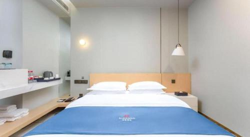 a bedroom with a large blue bed in it at Borrman Hotel Jining High-tech Huangtun in Jining