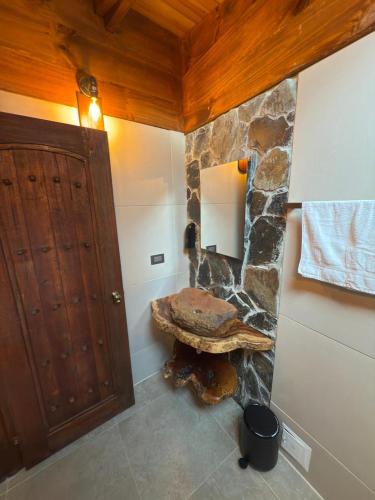 a bathroom with a stone wall and a wooden door at Casa Campestre Los Nevados Patio Bonito in Estación El Salto
