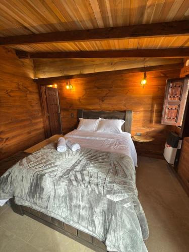 a bedroom with a large bed in a wooden cabin at Casa Campestre Los Nevados Patio Bonito in Estación El Salto