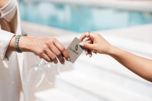 a bride and groom holding up a piece of paper at La Brise Luxury Suites in Néa Péramos