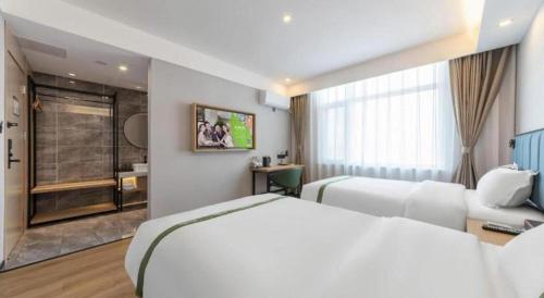 a hotel room with two beds and a bathroom at GreenTree Inn Express Qingdao Jiaodong International Airport in Qingdao