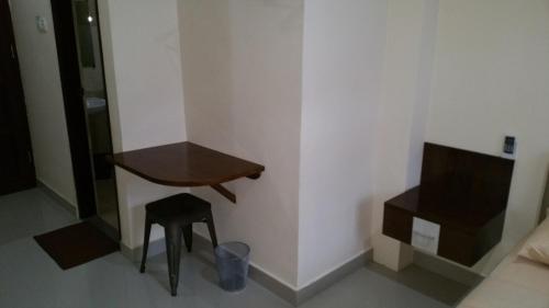 a small table and stool in a room with a television at Legenda Beril Hostel in Makassar