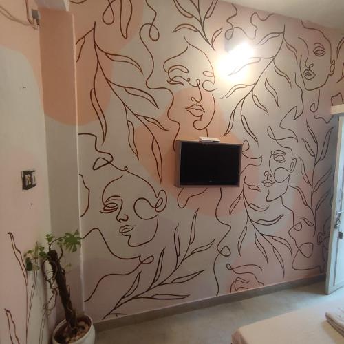 a wall mural in a room with a tv at Vanam Soulful Stays in Puducherry