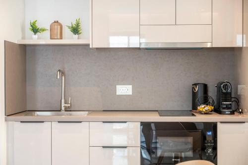 a kitchen with white cabinets and a sink at Unicos City Suites in Kos Town