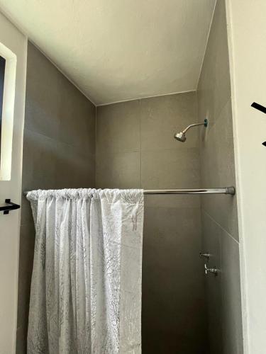 a shower with a white shower curtain in a bathroom at Departamento nuevo completo Zoologico GDL in Guadalajara