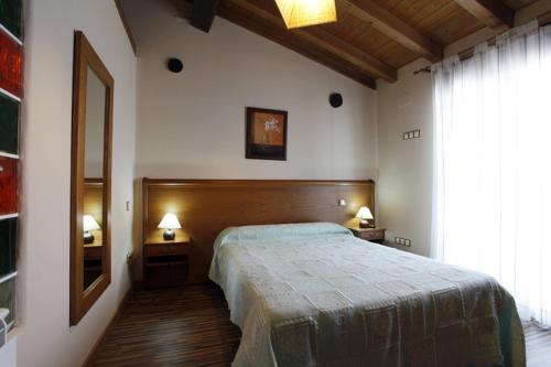 a bedroom with a bed and two night stands with lamps at Apartamentos Hervasypunto in Hervás