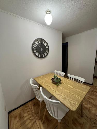 a dining room table with chairs and a clock on the wall at Departamento en Quillota in Quillota