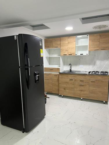 a kitchen with a black refrigerator and wooden cabinets at Alojamiento Privado en Avenida Principal in Manizales