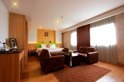 um quarto de hotel com uma cama, um sofá e uma cadeira em Sala View Hotel em Surakarta