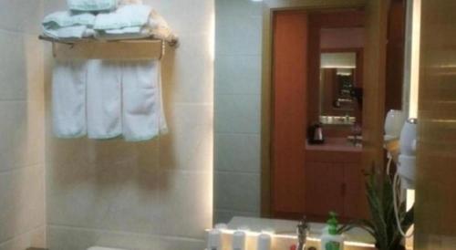 a bathroom with a sink and a mirror and towels at GreenTree Inn Nantong University Industrial Expo City Express Hotel in Nantong