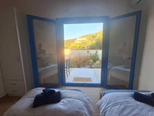 a room with two beds and a large window at Louloudi in Káto Alepokhórion