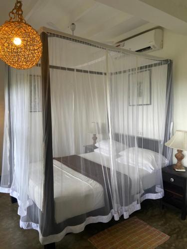 a bedroom with a canopy bed with white curtains at Lara's place in Unawatuna