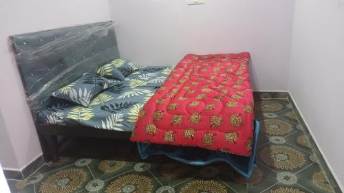 a bed with a red blanket on top of it at Kanha Homestay and restaurant in Dhanaulti