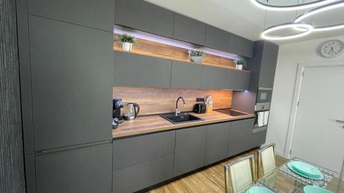 a kitchen with gray cabinets and a sink and a table at Тони апартмент in Burgas City