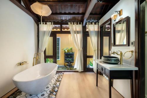 a bathroom with a large white tub and a sink at Hội An Wooden Retreat In Town in Hoi An