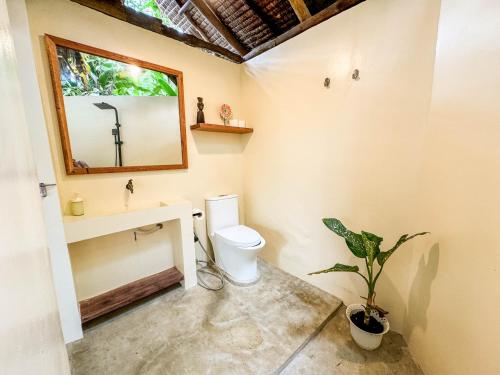 a bathroom with a toilet and a sink and a mirror at Zen Treehouse in General Luna