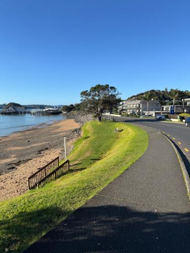 a road with a fence next to a beach at Sunset View Chalet in Paihia