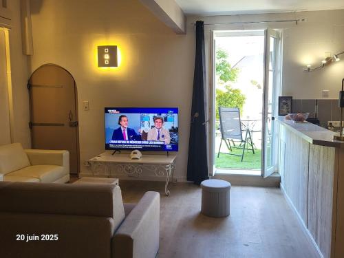 un salon avec une télévision à écran plat sur une table dans l'établissement Gîte Coté Village - le cœur du village avec piscine, à Salles-d'Aude