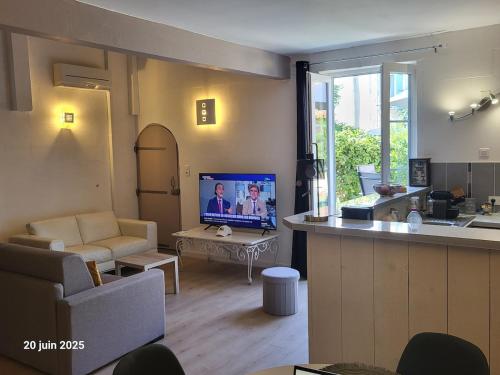 un salon avec une cuisine et un salon avec une télévision dans l'établissement Gîte Coté Village - le cœur du village avec piscine, à Salles-d'Aude