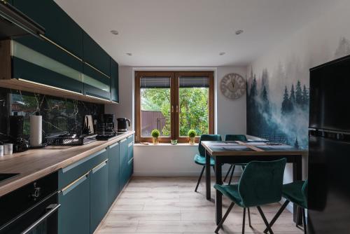 a kitchen with green cabinets and a table with chairs at Domek Pod Czereśnią in Szczawnica