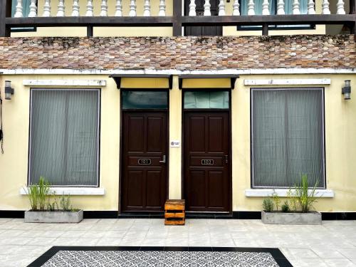 a building with two brown doors and two windows at October Hostel ChiangMai in Chiang Mai