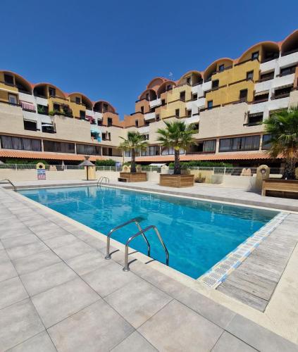 - une piscine en face d'un immeuble dans l'établissement L'Escapade Gruissanaise, appartement 1 chambre, loggia, climatisation, wifi avec piscines de mi-mai à mi-septembre dans résidence, à Gruissan