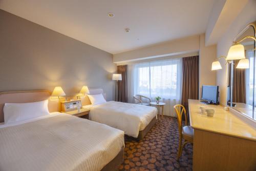 a hotel room with two beds and a television at Hotel Fujita Fukui in Fukui