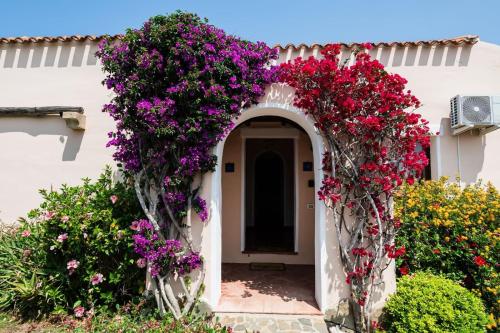 an archway with flowers on a white building at Villa Rosa - Piscina privata in Stintino