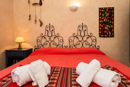 a bedroom with a red bed with two rolled towels at Villa Rosa - Piscina privata in Stintino