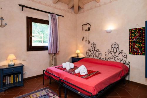 a bedroom with a red bed with a red bedspread at Villa Rosa - Piscina privata in Stintino