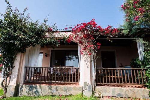 a house with a balcony with red flowers on it at Villa Rosa - Piscina privata in Stintino