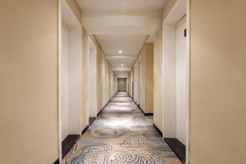 a hallway with a long corridor with white walls and a tile floor at Home Inn Huayi Selected Yellow Crane Tower Tang Hualin Branch in Wuhan