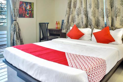a bedroom with a large bed with red pillows at Hotel O Homes Vardhan House 2 in Pune