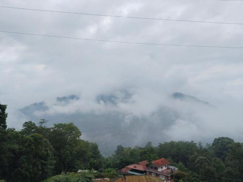 a foggy mountain with a house in the foreground at Edens Homestay in Gangtok
