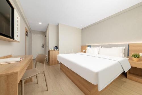 a bedroom with a large white bed and a desk at Home Inn Huayi Selected Yellow Crane Tower Tang Hualin Branch in Wuhan