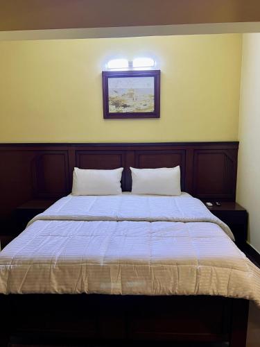 a bed with two pillows and a picture on the wall at Al Makkah Hotel in Karachi