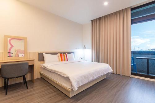 a bedroom with a bed and a desk and a window at Meet in Dongshan Homestay in Dongshan