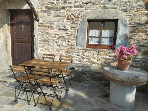 a wooden table and chairs in front of a stone building at Casa Mameleiro e Casa Kintal in A Pontenova