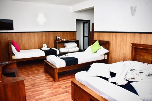 a room with three beds and a tv in it at Forest Edge Holiday Inn in Nuwara Eliya