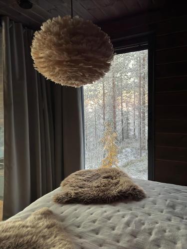 a bed with two furry pillows in front of a window at Villa Pikku Karhu in Kuusamo
