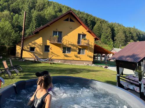a woman in a hot tub in front of a house at Casa Natalia Raisa Arieșeni in Arieşeni