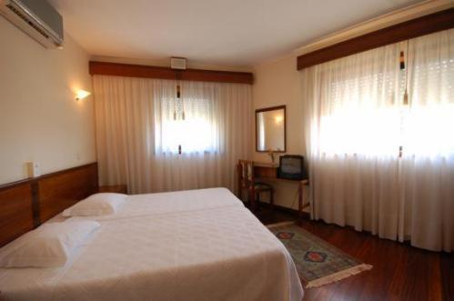 a bedroom with a large white bed and a window at Hotel O Cortiço in Sever do Vouga