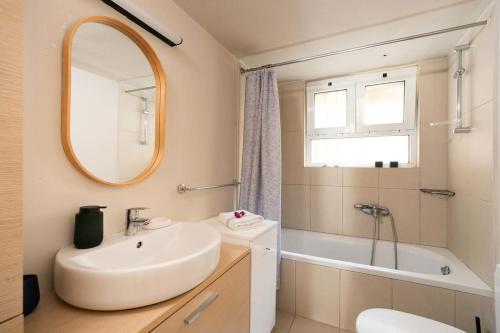 a bathroom with a sink and a tub and a mirror at Asmira Apartment by PaxosRetreats in Lákka