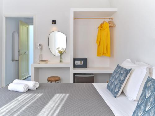a white bedroom with a bed and a mirror at Akrotiri Hotel in Parikia