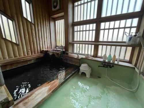 a bathroom with a pool of water in a room with windows at Hot Spring Inn Hyoutan in Kusatsu