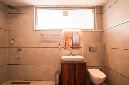 a bathroom with a sink and a toilet and a window at goSTOPS PLUS Gurugram, Baani Square in Gurgaon