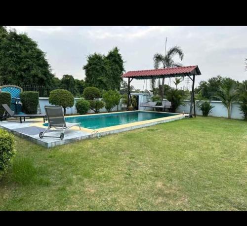 ein Pool in einem Hof mit einem Stuhl und einem Pavillon in der Unterkunft Pattaya Paradise Pool villa with Garden 3BR in Nong Prue