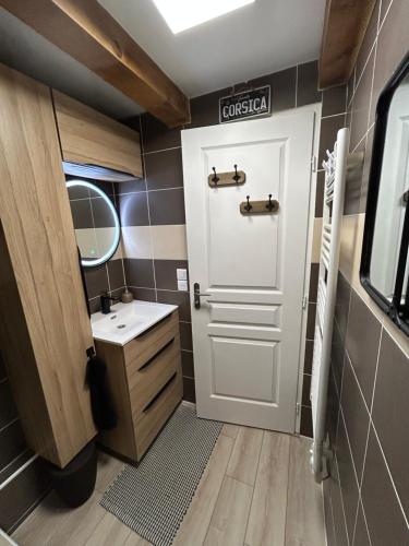 La salle de bains est pourvue d'une porte blanche et d'un lavabo. dans l'établissement Charmant Duplex Centre Village, à Saint-Cyr-sur-Mer