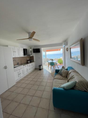 un salon avec un canapé bleu et une cuisine dans l'établissement studio climatisé les pieds dans l'eau, à Six-Fours-les-Plages